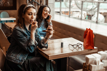 Cafes and bars. Two girls are sitting at a cafe table. Discussion of shopping. Girlfriends in a cafe.