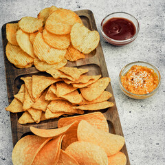 Chips, snacks and crackers on a wooden board. Fast food.