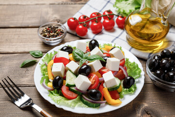 Greek salad with cheese and fresh vegetables on wooden background.