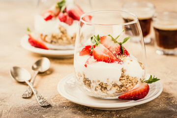 Healthy breakfast with oatmeal granola, strawberries and yogurt on light brown background. Retro style toned.