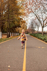 Fall season, hello autumn. Stylish 7 years old girl walking in the empty park among golden trees