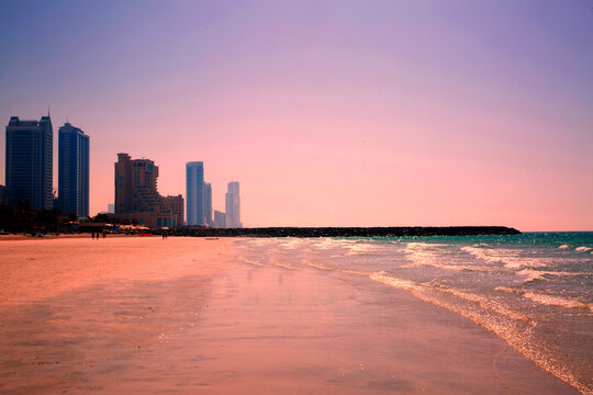 Beautiful violet pink sunset at the beach, modern skyscrapers.