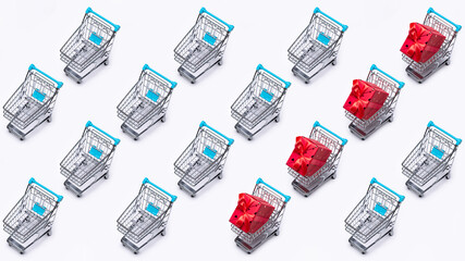 Background pattern. A shopping cart (toy), cloned with gifts in a large box, packed in red paper. Copy space, white background.