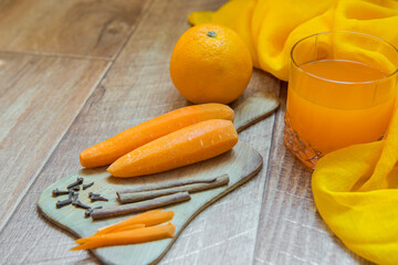 Orange and carrot juice. Carrot juice. Healthy food, healthy drink. Orange juice in a glass and next Orang, peeled carrots. healthy eating for breakfast. Wood background