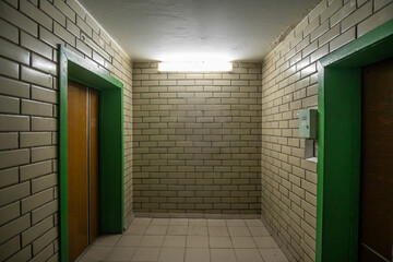 Room with elevators of a Soviet apartment building of the 80s, lined with glazed ceramic tiles.