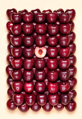 Fresh sweet cherry with half a berry in the center on yellow background. Creative art pattern wallpaper.