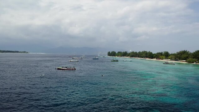 Summer time in the Gili Travangan Island with cruise boats. Aerial drone shot of the island nearby.