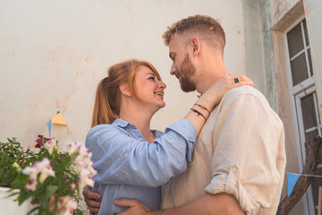 young couple is spending time on a balcony of their flat.  couple smiling and spending leisure time together. man and woman holding each other