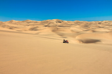 Quad driving in sand desert. ATV standing in middle of nowhere in sand dunes desert with skid marks. Africa, Namibia, Namib, near Walvis Bay, Swakopmund.