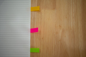 notebook with small colorful stickynote pad on the egde on the wooden table office background