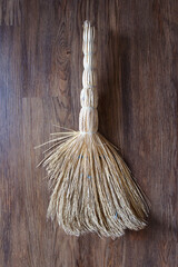 Old straw besom on a wooden background. Traditional decrepit broom for floor. shaggy broom on the...