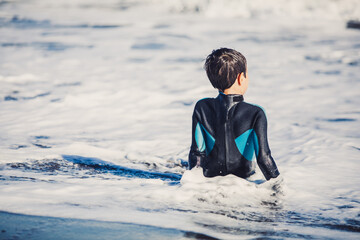 A young boy enjoying a funny surf day in the shore of a sunny beach in their coastal holidays