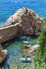 People practicing paddle surf in a cove on the Costa Brava during the summer