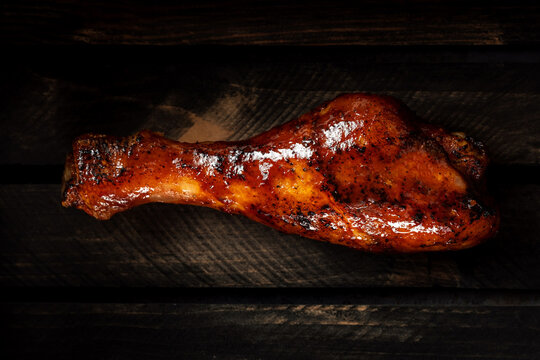 Grilled chicken leg in barbecue sauce on a dark wooden background