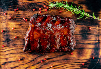 Grilled pork ribs with barbecue sauce on a wooden Board with spices and rosemary, top view