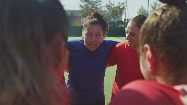 Manager joining hands with womens soccer team during motivational pep talk before match - shot in slow motion