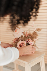 Artificial flowers in a girl's hands. Decorative flowers as a gift. Florist makes flowers. Decorative flowers and hands of a girl.