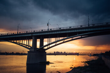 Urban evening landscape. Road bridge over the Ob river at sunset. Fantastic clouds in the dark sky.