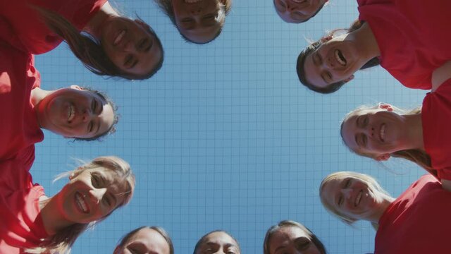 Portrait of womens soccer team joining hands during motivational pep talk shot from low angle below - shot in slow motion
