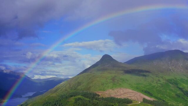 A rainbow appearing over the pap of glencoe and the village of glencoe in the argyll region of the highlands of Scotland during a summer rainfall