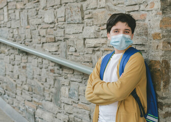 kid with medical mask and backpack waiting at the school door