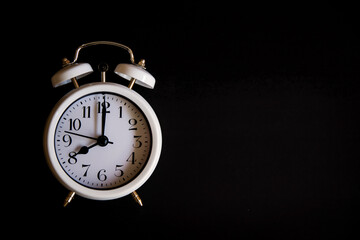 Vintage alarm clock with old white bells, with black background. Concept of a retro watch. Copy space