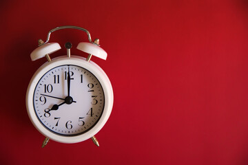 Vintage alarm clock with old white bells, with red background. Concept of a retro watch. Copy space