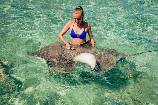 happy young girl swimming with two Stingray in ocean