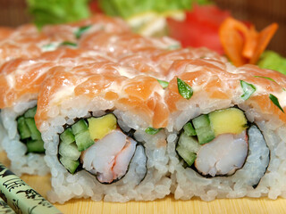Japanese roll with salmon, shrimp, avocado and cucumber on a wooden tray close-up