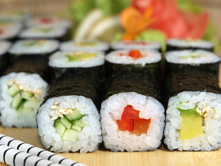 Japanese maki roll set with avocado, cucumber and red bell pepper on a wooden tray close-up