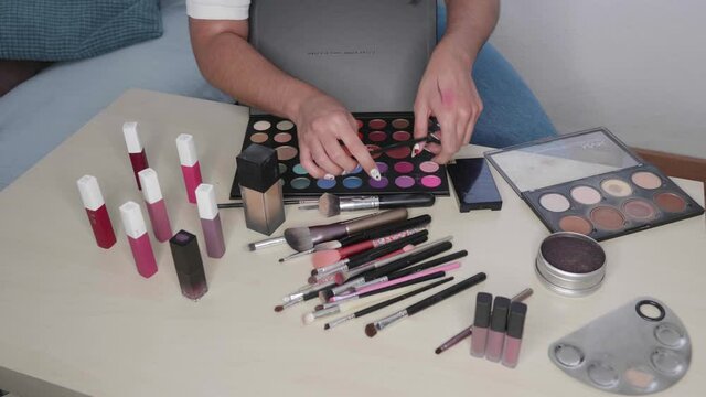 Hands holding cosmetics. Fashion blogger presenting makeup cosmetics at home. Influencer in the concept of social media.