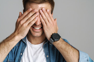 Portrait of cheerful unshaven man laughing and covering his eye