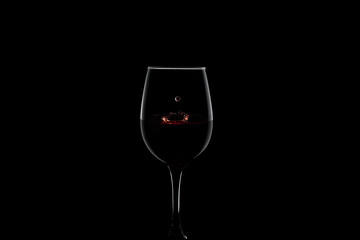 Naklejka na ściany i meble Glass with red wine. red wine splash with crown and drop on black background