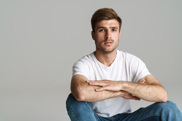Portrait of redhead man looking at camera while sitting on floor