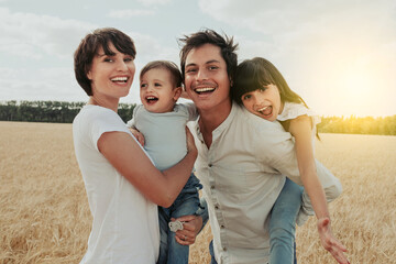 portrait of a happy and smiling family in a wheat field under a sunset