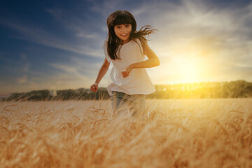 a girl smiling and running in a wheat field under a sunset