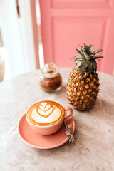 Pink cup of cappuccino on marble table background. Love latte art on the top of it.