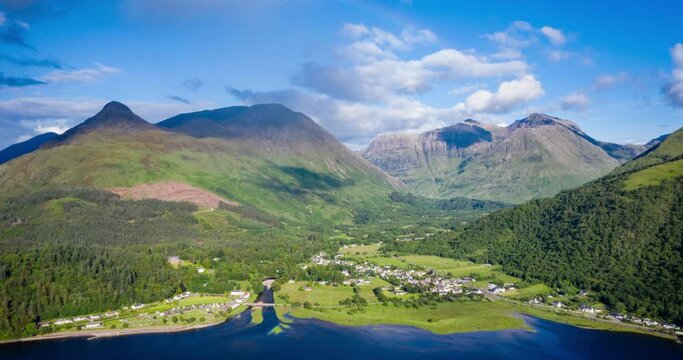 A rainbow appearing over the pap of glencoe and the village of glencoe in the argyll region of the highlands of Scotland during a summer rainfall
