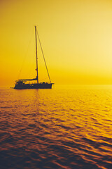 Silhouette of a sailing boat in sunset / sunrise time and ocean horizon.