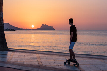 Teenager with his longboard at dawn near the ocean, sea © Chebix