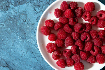 a lot of sweet fresh red raspberries on a plate from the market or garden