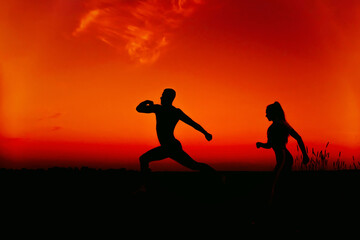 Fototapeta na wymiar silhouettes of a couple running in nature in summer at sunset