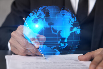 Businessman in suit signs contract. Double exposure with world map hologram. Man signing agreement...