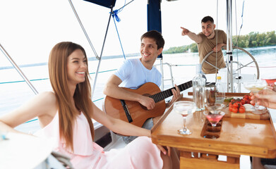 Group of happy friends drinking vodka cocktails at boat party outdoor, cheerful and happy. Young people having fun in sea tour, youth and summer vacation concept. Alcohol, vacation, resting.