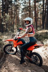 Modern young tattooed racer girl with pink hair riding on her motorcycle in off road adventure