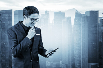 Young handsome businessman in suit and glasses using phone and thinking how to tackle the problem, new career opportunities, MBA. Singapore on background. Double exposure.