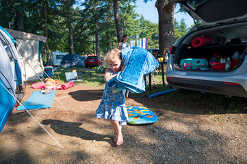 Cute blonde girl helping around tent pitch at camping resort.