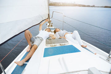 Young cheerful caucasian couple resting at boat party outdoor, smiling and happy. Adventure in sea tour, youth and summer vacation concept. Relations, love, romantic concept. Good vibes and emotions.