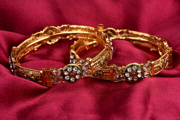 Indian golden Bangles. Bracelet with diamonds and stones on a red satin background, Indian Traditional Jewellery,Style, fashion and design of jewelry