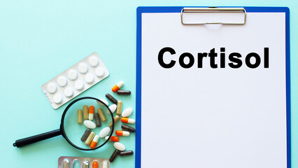 A clipboard with paper lies on a table near drugs and a syringe. Inscription CORTISOL. Medical concept.